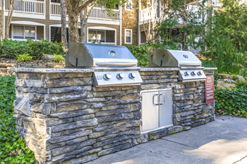 a backyard barbecue area with a stone wall and two stove at Elan at Mallard Creek Apartment Homes, Charlotte, North Carolina